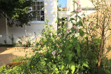 Diseño de jardín de secano costero pequeño en patio con macetero elevado, exposición parcial al sol y gravilla