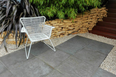 Photo of a medium sized contemporary back formal partial sun garden in Other with a retaining wall and natural stone paving.