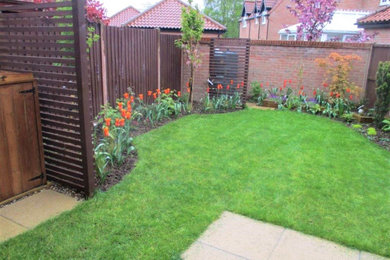 Small contemporary back formal full sun garden for spring in Other with a flowerbed and concrete paving.