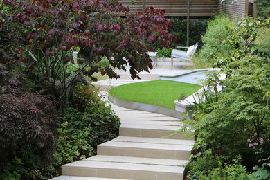 Photo of a contemporary back fully shaded garden in London with a pathway and natural stone paving.