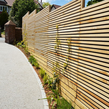 Contemporary driveway on a slope fenced in using Western Red Cedar Slatted Scree