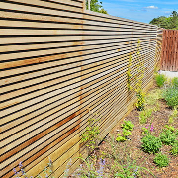 Contemporary driveway on a slope fenced in using Western Red Cedar Slatted Scree