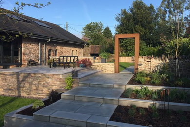 This is an example of a medium sized contemporary back formal partial sun garden for spring in Other with a garden path and natural stone paving.