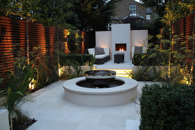 Photo of a medium sized contemporary courtyard formal partial sun garden for spring in London with a fire feature and natural stone paving.