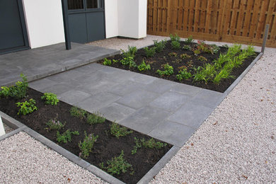 Diseño de jardín contemporáneo de tamaño medio en patio delantero con exposición parcial al sol y adoquines de hormigón