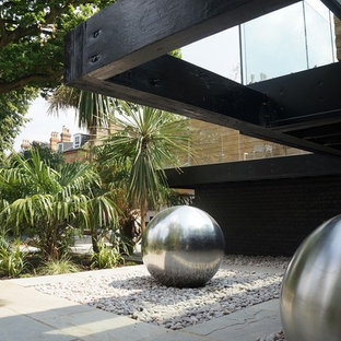 Inspiration for a large contemporary back formal full sun garden in London with natural stone paving.