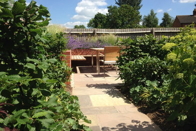 Imagen de jardín de estilo americano en primavera en patio trasero con adoquines de piedra natural