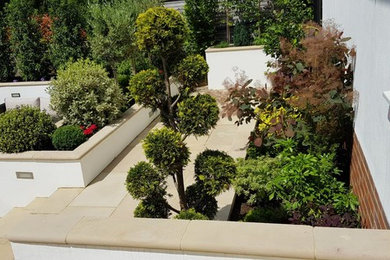 Idée de décoration pour un grand jardin arrière design l'été avec une exposition ombragée et des pavés en pierre naturelle.