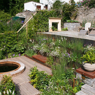 Country back formal full sun garden for summer in Other with a retaining wall and natural stone paving.