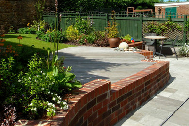 Modelo de jardín actual de tamaño medio en patio trasero con muro de contención, exposición parcial al sol y adoquines de piedra natural