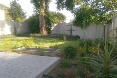 This is an example of a small modern back formal full sun garden for summer in Sussex with a water feature and decking.