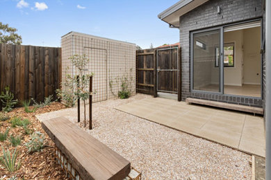 Photo of a small urban back xeriscape full sun garden for spring in Melbourne with a garden path and gravel.