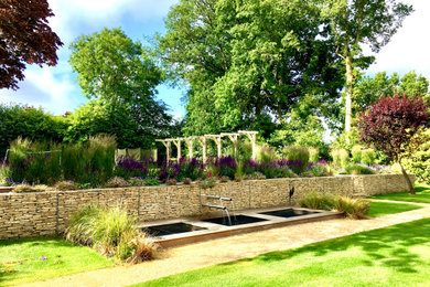 Diseño de jardín campestre grande en verano en patio trasero con jardín francés, estanque, exposición parcial al sol y gravilla