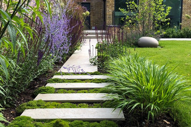 Design ideas for a medium sized contemporary back formal partial sun garden for summer in London with a retaining wall and natural stone paving.