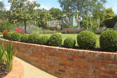 Diseño de camino de jardín de estilo de casa de campo de tamaño medio en verano en patio trasero con jardín francés, exposición parcial al sol y gravilla