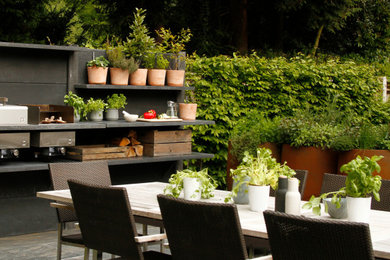 Modelo de jardín minimalista de tamaño medio en verano en patio trasero con jardín francés, exposición parcial al sol y adoquines de piedra natural