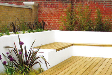 This is an example of a medium sized contemporary back full sun garden for summer in London with decking.
