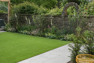 This is an example of a medium sized contemporary back formal partial sun garden for summer in Edinburgh with lawn edging and natural stone paving.