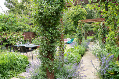 Ejemplo de jardín de estilo americano de tamaño medio en verano en patio trasero con jardín francés, exposición parcial al sol y adoquines de piedra natural