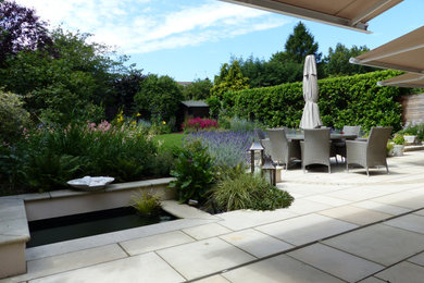 Ejemplo de jardín moderno en patio trasero con jardín francés, exposición total al sol y adoquines de piedra natural