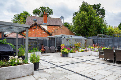 Mittelgroßer, Halbschattiger Moderner Garten im Sommer, hinter dem Haus mit Hochbeet und Betonboden in Surrey