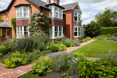 This is an example of a medium sized front formal partial sun garden for spring in Wiltshire with a garden path and brick paving.