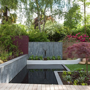 This is an example of a large contemporary back formal garden in London with a pond and decking.