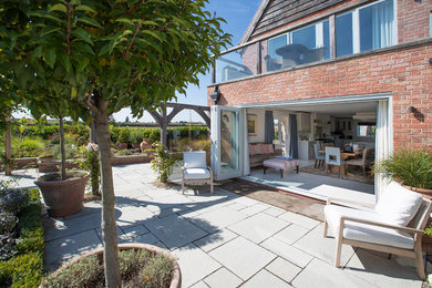 Expansive contemporary front patio in West Midlands with natural stone paving.