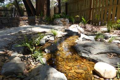 Halbschattiger Rustikaler Garten mit Wasserspiel in Sonstige