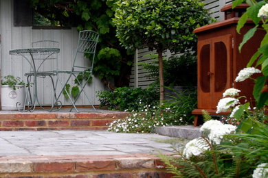 Foto de jardín bohemio pequeño en verano en patio trasero con jardín francés, chimenea, exposición parcial al sol y adoquines de piedra natural