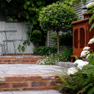 Geometrischer, Kleiner, Halbschattiger Stilmix Garten im Sommer, hinter dem Haus mit Kamin und Natursteinplatten in Kent