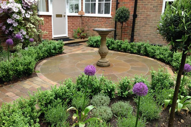 This is an example of a mid-sized traditional partial sun front yard stone formal garden in Surrey for summer.