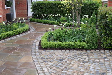 Photo of a classic front driveway partial sun garden in London with natural stone paving.