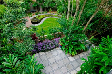 Ejemplo de jardín exótico grande en patio trasero con jardín francés, fuente y adoquines de hormigón