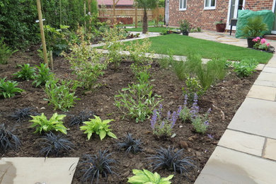 Photo of a large contemporary back xeriscape partial sun garden for winter in Essex with a vegetable patch and natural stone paving.
