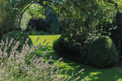 Inspiration för klassiska formella trädgårdar i delvis sol på våren, med en trädgårdsgång