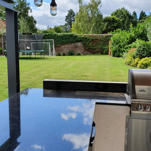 Großer Moderner Garten hinter dem Haus mit Kamin und direkter Sonneneinstrahlung in Surrey