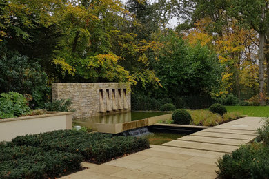 Photo of a large contemporary back formal partial sun garden in London with a flowerbed and decorative stones.