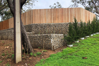 На фото: участок и сад на переднем дворе в стиле рустика с подпорной стенкой с