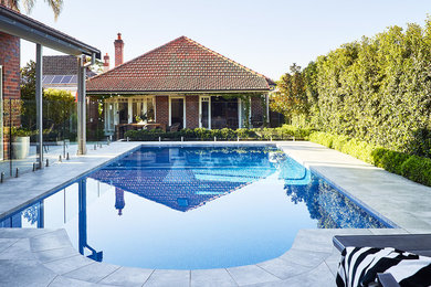 Inspiration for a large contemporary back swimming pool in Sydney with natural stone paving.