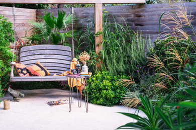 Photo of a small rustic drought-tolerant, privacy and partial sun backyard stone landscaping in London for summer.