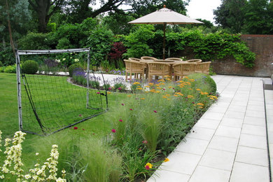 Large contemporary back full sun garden for summer in London with natural stone paving.
