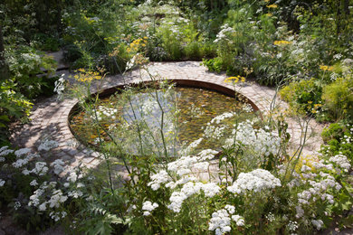 Ejemplo de jardín de secano de estilo de casa de campo pequeño en verano en patio trasero con estanque, exposición total al sol y adoquines de piedra natural