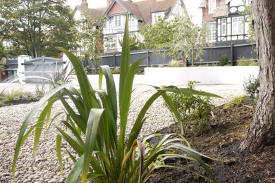 Photo of a medium sized mediterranean front xeriscape full sun garden in Sussex with a retaining wall and natural stone paving.