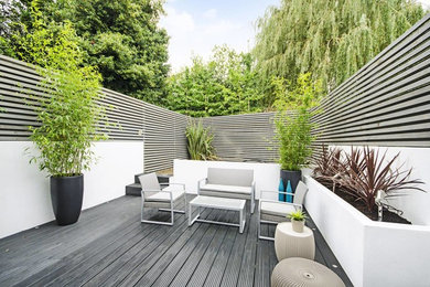 This is an example of a medium sized contemporary back garden in London with decking.
