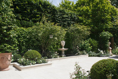Medium sized traditional courtyard formal full sun garden for summer in London with natural stone paving.
