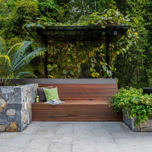 Idee per un grande giardino tropicale esposto a mezz'ombra dietro casa in estate con pavimentazioni in pietra naturale e un muro di contenimento