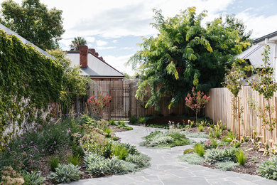 Modelo de jardín de secano actual de tamaño medio en primavera en patio trasero con exposición total al sol y adoquines de piedra natural