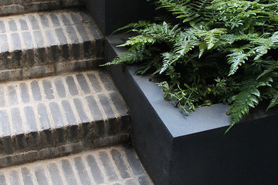 Design ideas for a small contemporary front partial sun garden in London with brick paving.