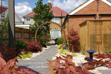 Photo of a medium sized contemporary back partial sun garden for spring in London with natural stone paving.